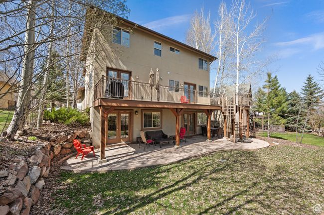Rear view of property featuring a lawn, french doors, a patio, stucco siding, and stairs | Image 31