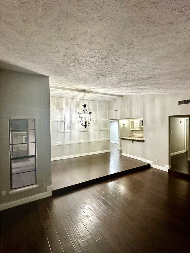 Unfurnished dining area with a textured ceiling, a chandelier, and wood finished floors | Image 4