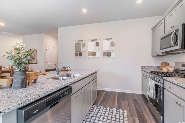 Kitchen featuring appliances with stainless steel finishes, dark wood-style flooring, gray cabinetry, light stone countertops, and recessed lighting | Image 4
