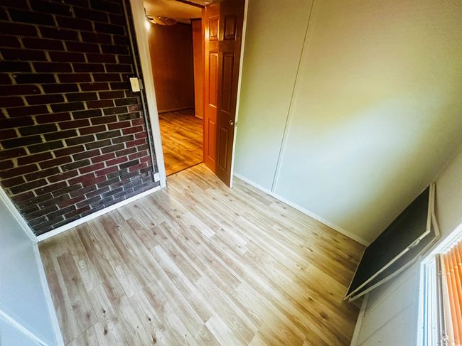 Empty room with light wood finished floors, baseboards, and brick wall | Image 12