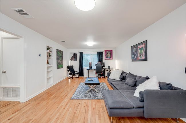 Living area with a desk, light wood-type flooring, built in shelves, and baseboards | Image 33