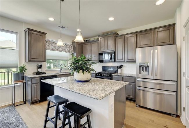 Kitchen featuring black appliances, a sink, light wood-style flooring, a kitchen island, and dark brown cabinets | Image 10