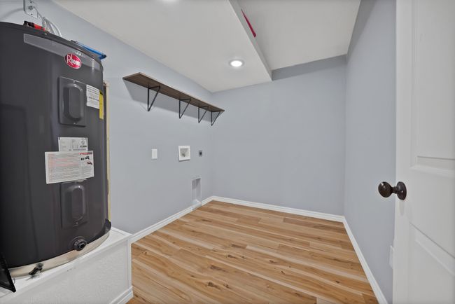 Washroom featuring electric water heater, light wood-style flooring, washer hookup, electric dryer hookup, and recessed lighting | Image 15