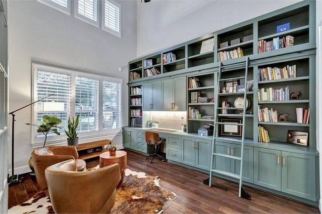 Stunning downstairs study features soaring ceilings, custom built-ins in 2022 with including a rolling ladder to easily reach all the bookshelves. Abundant natural light, and a cozy seating area—perfect for work or relaxation. | Image 8
