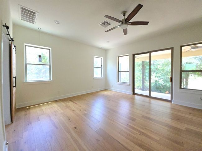 Empty room with a barn door, a ceiling fan, light wood-type flooring, baseboards, and recessed lighting | Image 13