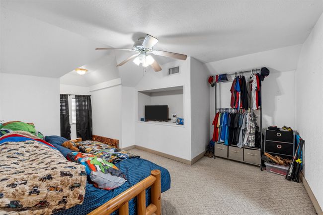 Carpeted bedroom with a ceiling fan, a textured ceiling, lofted ceiling, baseboards, and visible vents | Image 15