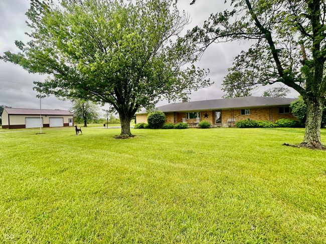 view of front facade featuring a detached garage, a front yard, an outdoor structure, and brick siding | Image 5
