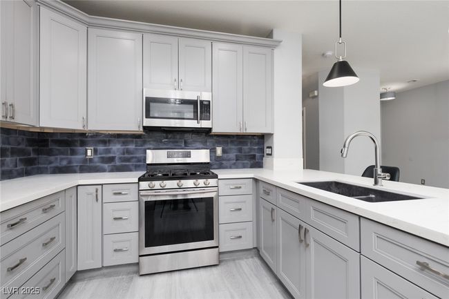 Kitchen featuring stainless steel appliances, light countertops, a sink, and gray cabinets | Image 10