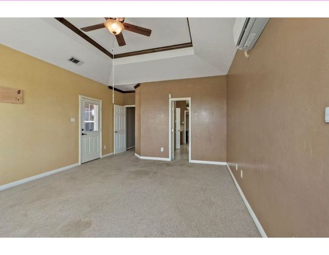Unfurnished bedroom featuring a raised ceiling, carpet, a wall mounted AC, and ceiling fan | Image 12