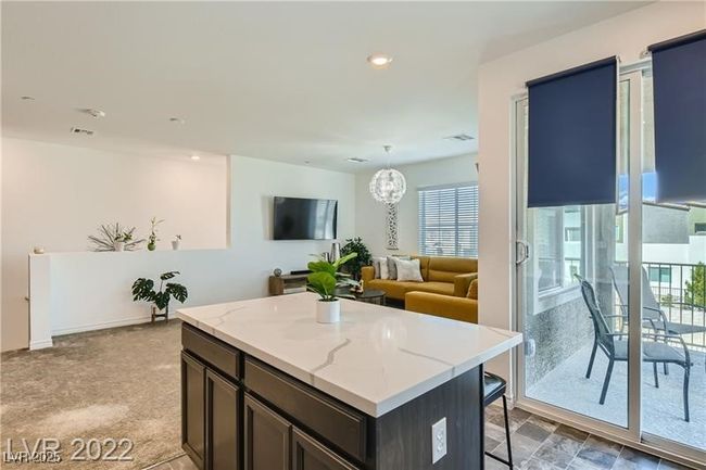 Kitchen featuring a breakfast bar, dark brown cabinetry, a center island, light stone countertops, and recessed lighting | Image 6