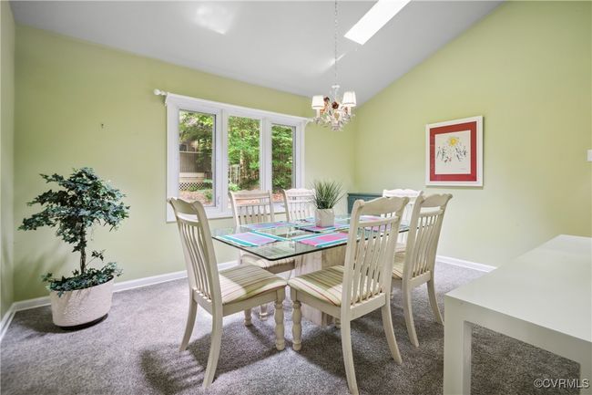 Dining area featuring vaulted ceiling, a chandelier, carpet flooring, and a skylight | Image 9