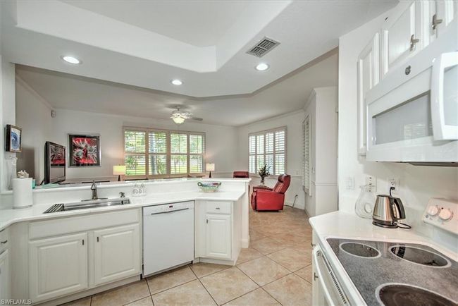 Kitchen with a sink, a peninsula, white appliances, visible vents, and white cabinets | Image 11