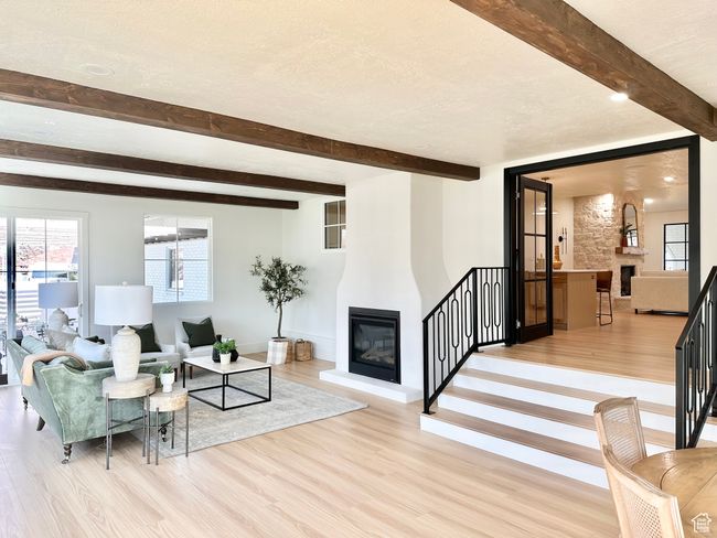 Living room featuring a fireplace, light wood-type flooring, beamed ceiling, stairs, and a textured ceiling | Image 13