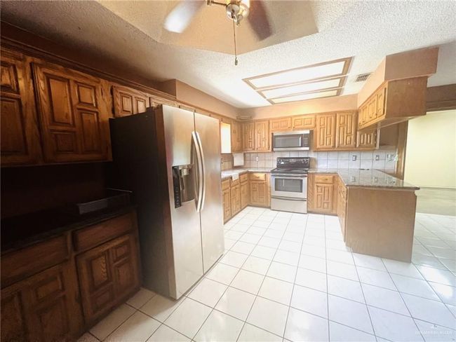 Kitchen with tasteful backsplash, ceiling fan, appliances with stainless steel finishes, and a textured ceiling | Image 8