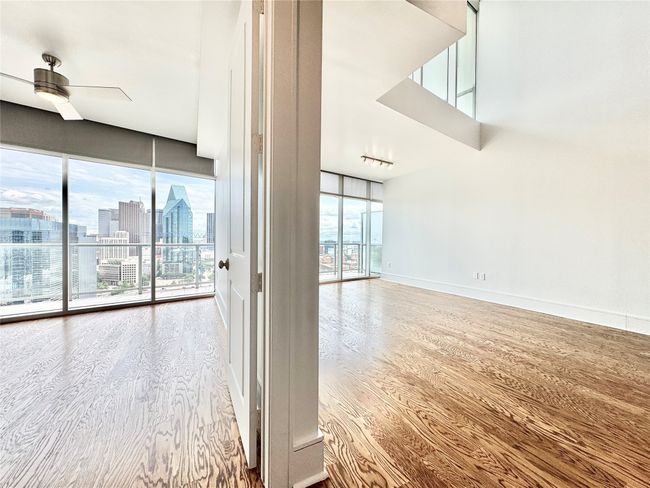 Spare room featuring a ceiling fan, wood finished floors, baseboards, and a city view | Image 23