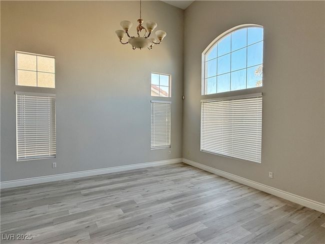 Empty room featuring a notable chandelier, baseboards, light wood-type flooring, and a towering ceiling | Image 5