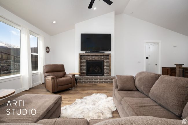Living room featuring ceiling fan, high vaulted ceiling, light wood-type flooring, and a fireplace | Image 9