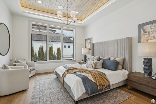 Bedroom with a raised ceiling, wooden ceiling, a notable chandelier, and wood finished floors | Image 24