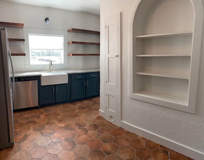 Kitchen with open shelves, stainless steel appliances, blue cabinetry, and light stone counters | Image 9