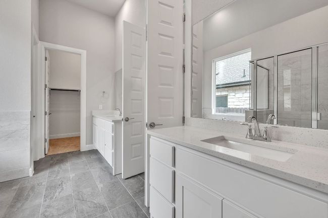 Bathroom featuring a stall shower, a walk in closet, two vanities, and a sink | Image 17