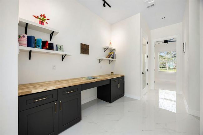 This versatile bonus space is ideal for a home office or dedicated homework area, featuring a built-in desk with ample storage, floating shelves for organization, and sleek finishes. Natural light and a clean, modern design make it both functional and inviting. | Image 34