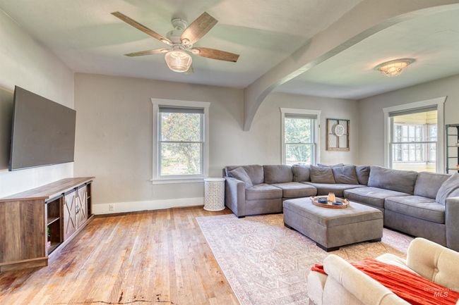 Living area featuring arched walkways, light wood-style flooring, plenty of natural light, and a ceiling fan | Image 13
