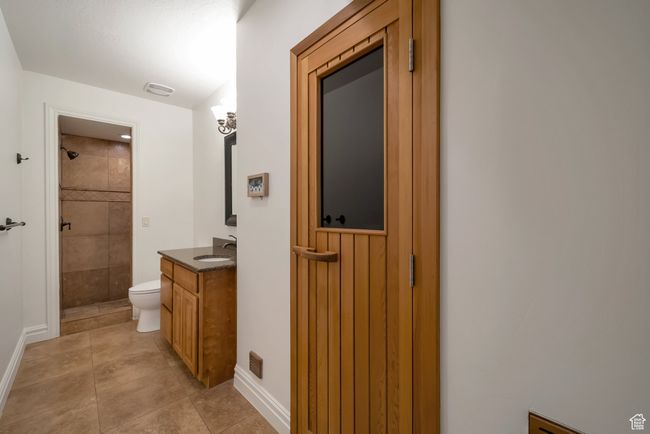Bathroom with baseboards, toilet, tile patterned floors, vanity, and tiled shower | Image 33