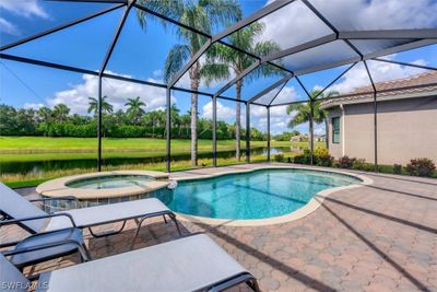 View of swimming pool featuring an in ground hot tub, glass enclosure, and a patio area | Image 1