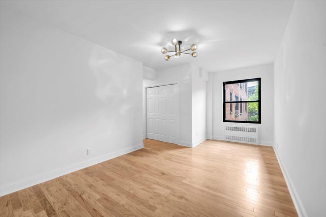 Spare room with radiator, a chandelier, and light wood-style flooring | Image 11