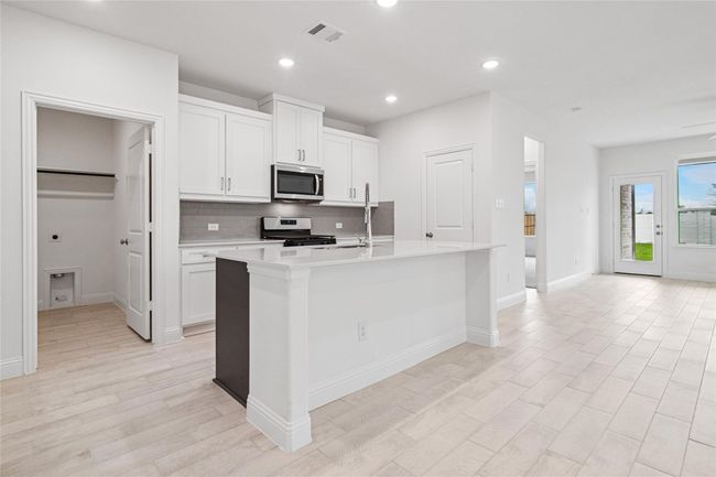 Kitchen with tasteful backsplash, a center island with sink, white cabinets, recessed lighting, and gas range oven | Image 26
