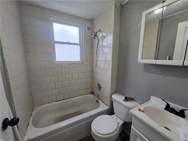 Full bathroom with a textured wall, toilet, tub / shower combination, and vanity | Image 16
