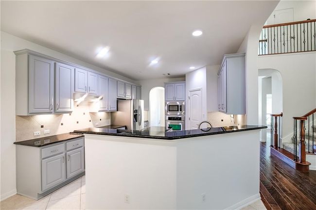 Kitchen featuring appliances with stainless steel finishes, arched walkways, gray cabinets, under cabinet range hood, and a peninsula | Image 11