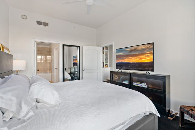 Bedroom with ceiling fan, dark wood-style flooring, visible vents, baseboards, and connected bathroom | Image 12