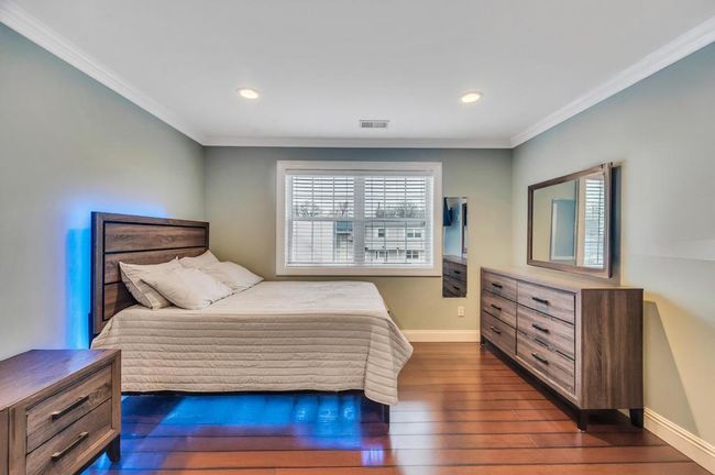 Bedroom with ornamental molding, dark wood-type flooring, baseboards, and visible vents | Image 14