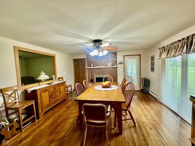dining space featuring a ceiling fan, dark wood-style flooring, a brick fireplace, and a baseboard radiator | Image 14