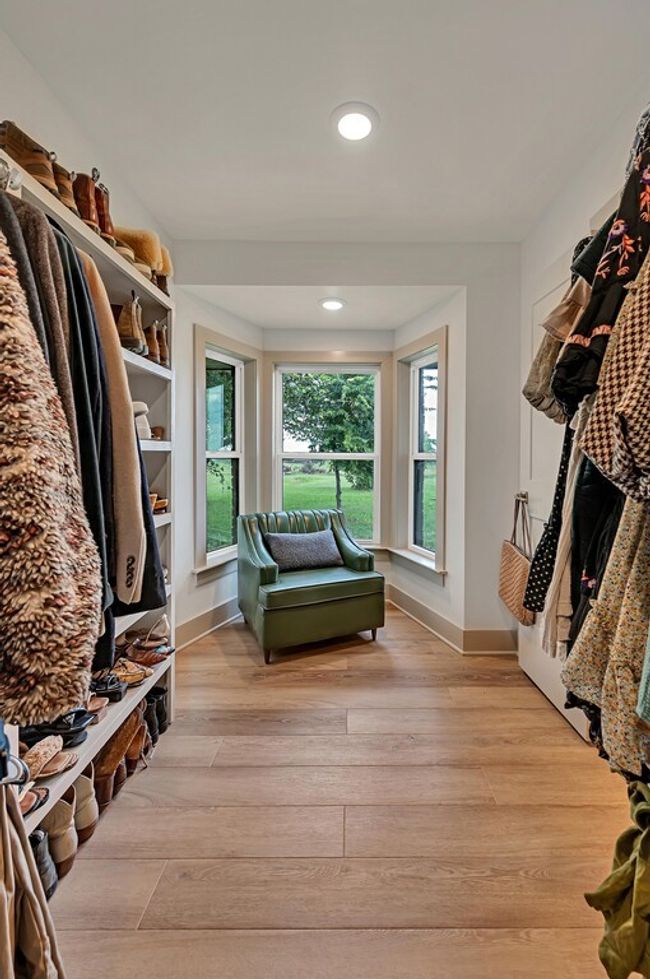 Spacious Primary walk in closet featuring light wood-style floors and seating area | Image 28