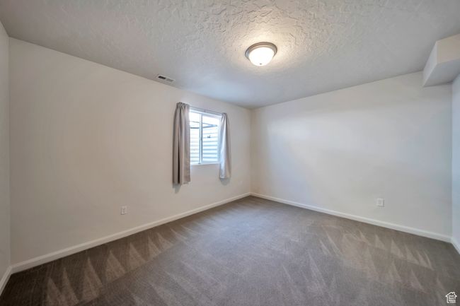 Empty room featuring baseboards, visible vents, dark carpet, and a textured ceiling | Image 23