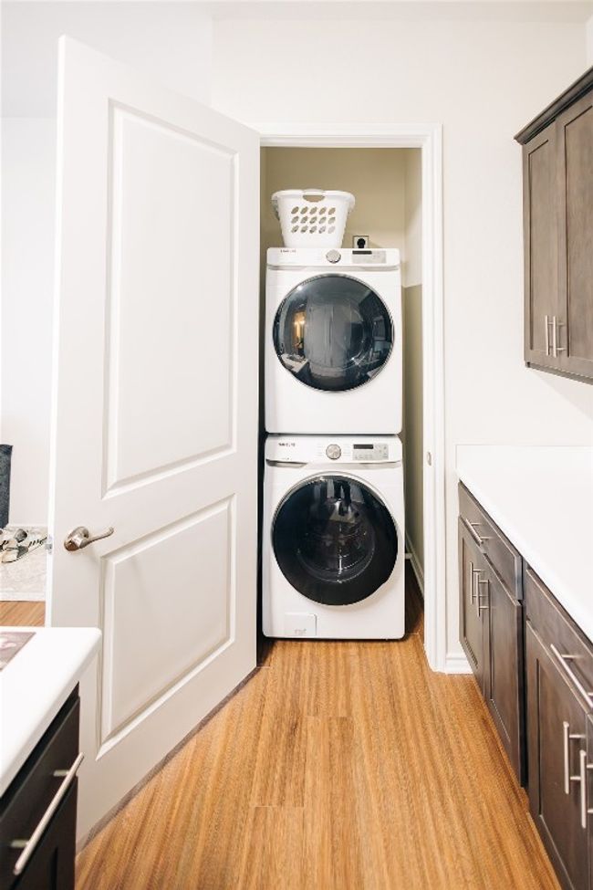 Washroom featuring stacked washing machine and dryer and light wood-style floors | Image 7