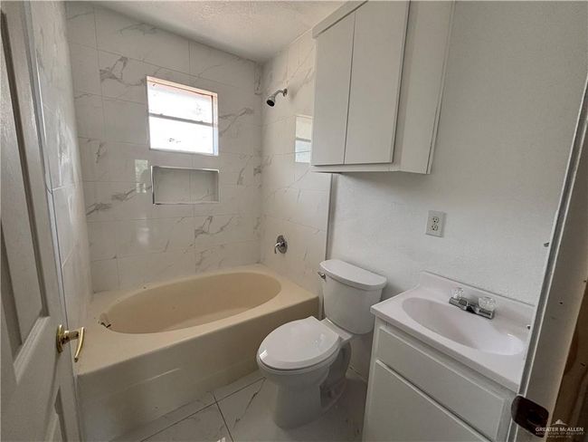 Full bath featuring marble look tile flooring, toilet, vanity, and shower / tub combination | Image 6