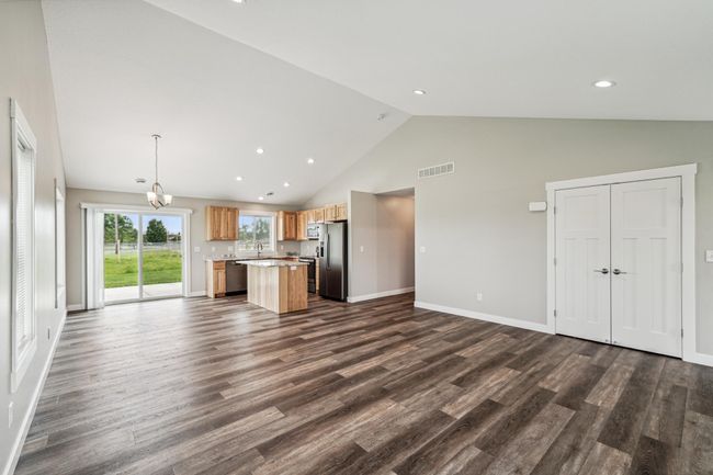Home features an open floor plan with LVP flooring throughout, vaulted ceilings, birch cabinets, granite countertops, center island and S.S. appliances, 3 bedroom on one level, and concrete patio off the dining room. | Image 7