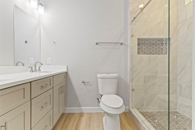 A stunning primary bathroom with a sleek double vanity, a luxurious shower, and radiant natural light. | Image 22