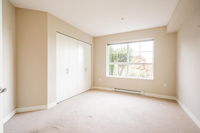 Unfurnished bedroom with a closet, baseboards, a baseboard heating unit, and light carpet | Image 16
