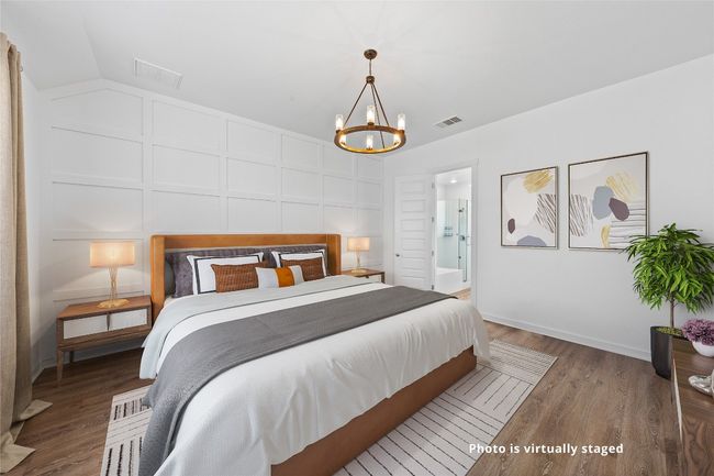 Bedroom featuring an inviting chandelier, wood finished floors, vaulted ceiling, and visible vents | Image 6