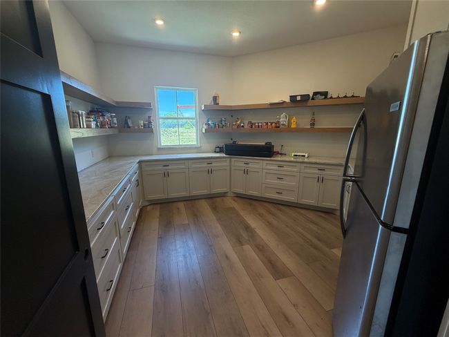 Kitchen with open shelves, freestanding refrigerator, wood finished floors, white cabinetry, and recessed lighting | Image 22
