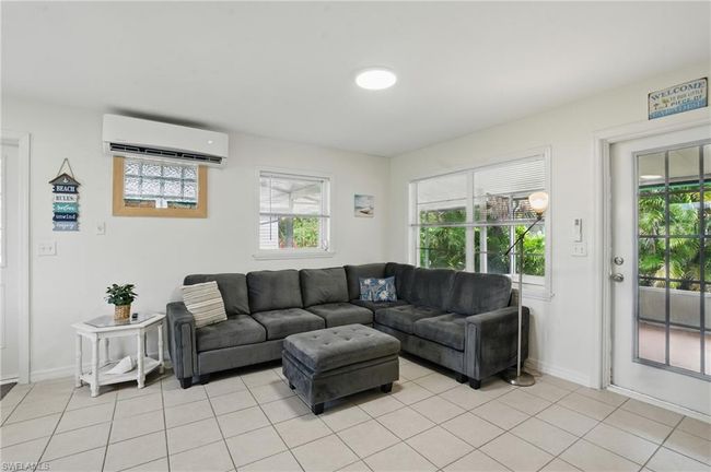 Living area with a wall mounted AC and light tile patterned floors | Image 17
