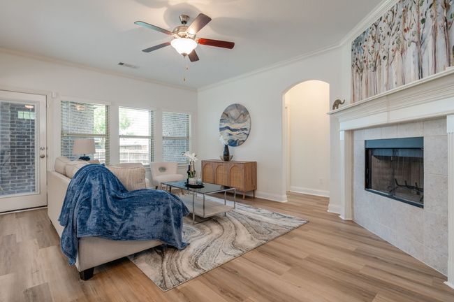 Living room featuring arched walkways, crown molding, ceiling fan, wood finished floors, and a tiled fireplace | Image 11