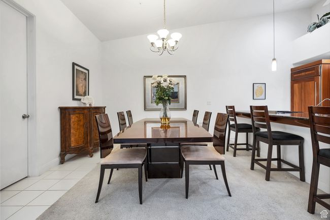 Dining room with high vaulted ceiling, baseboards, a notable chandelier, and light tile patterned flooring | Image 8