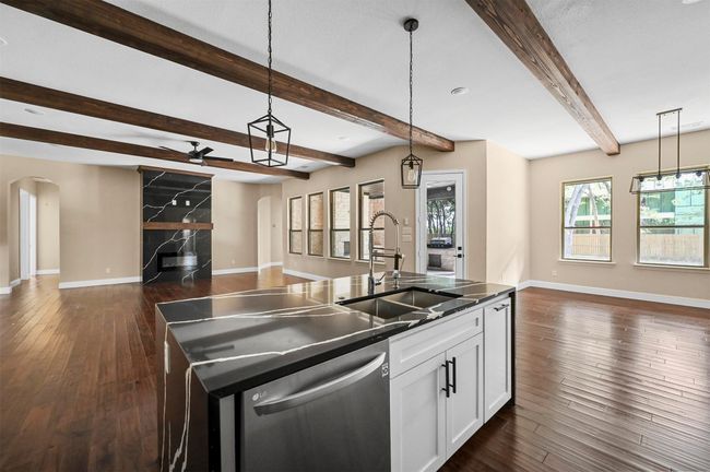 Kitchen with arched walkways, dark wood-style flooring, a sink, open floor plan, and dishwasher | Image 30