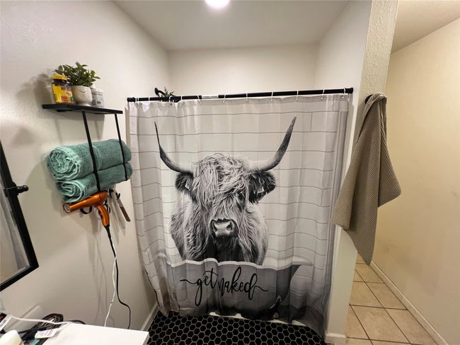 Bathroom with a shower with curtain, tile patterned floors, and baseboards | Image 19