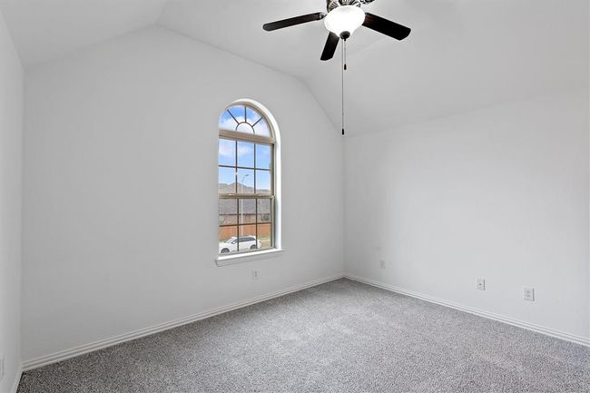 This charming bedroom boasts a high sloped ceiling, an elegant arched window that lets in plenty of natural light, and cozy carpet for added comfort. | Image 16